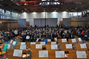 Die Halle einmal aus ungewohnter Perspektive - Blick von der leeren Bühne auf die sich füllenden Zuschauerreihen. Auf den Notenständern festgeklebt ist das Konzertprogramm mit Anweisungen zur Sitzverteilung